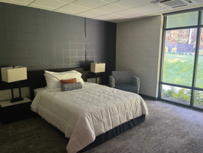 LiUNA dorm room, looks like a nice hotel room with a large bed, side tables, lamps, and a window